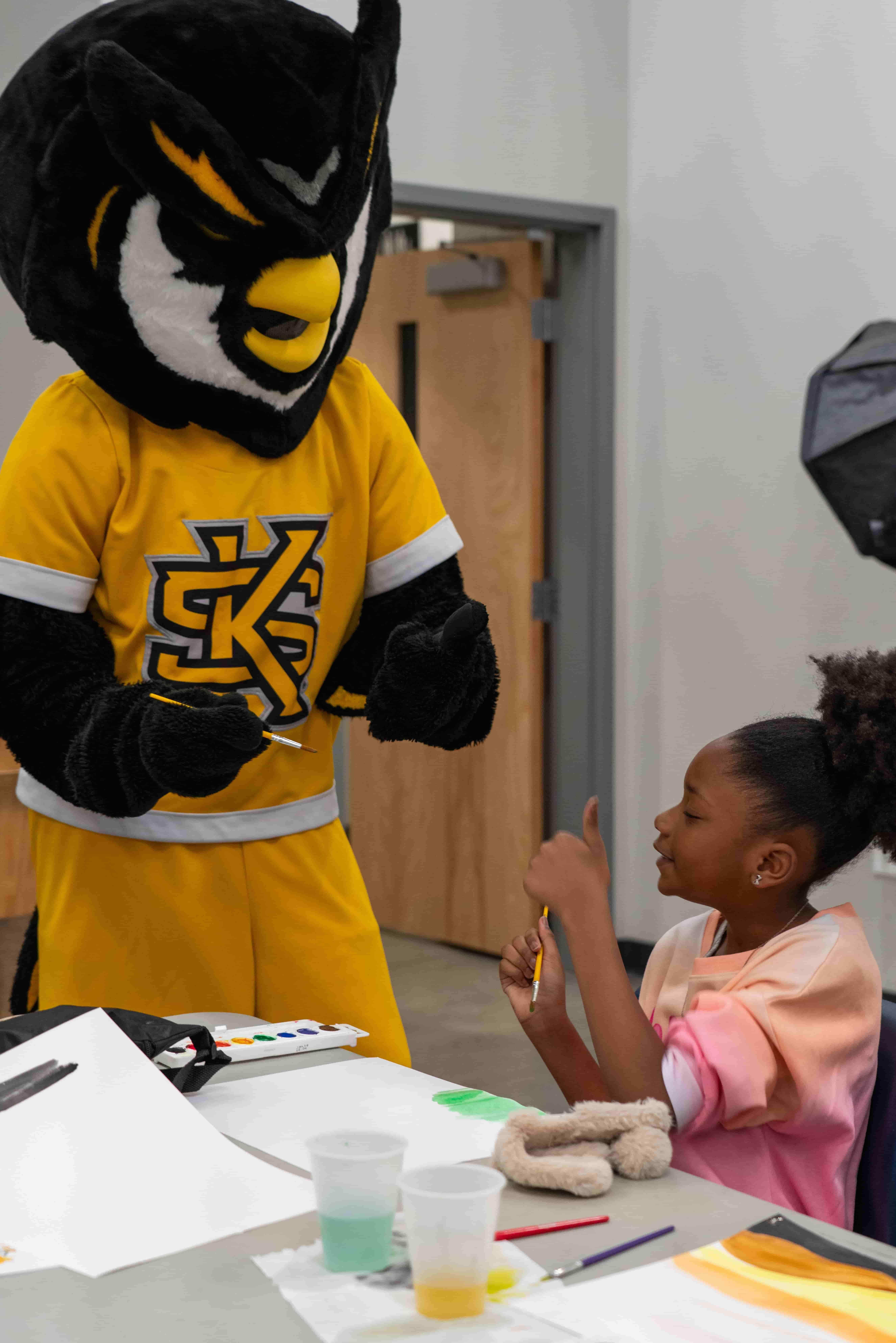 KSU mascot Scrappy the Owl painting with a young girl.   / 