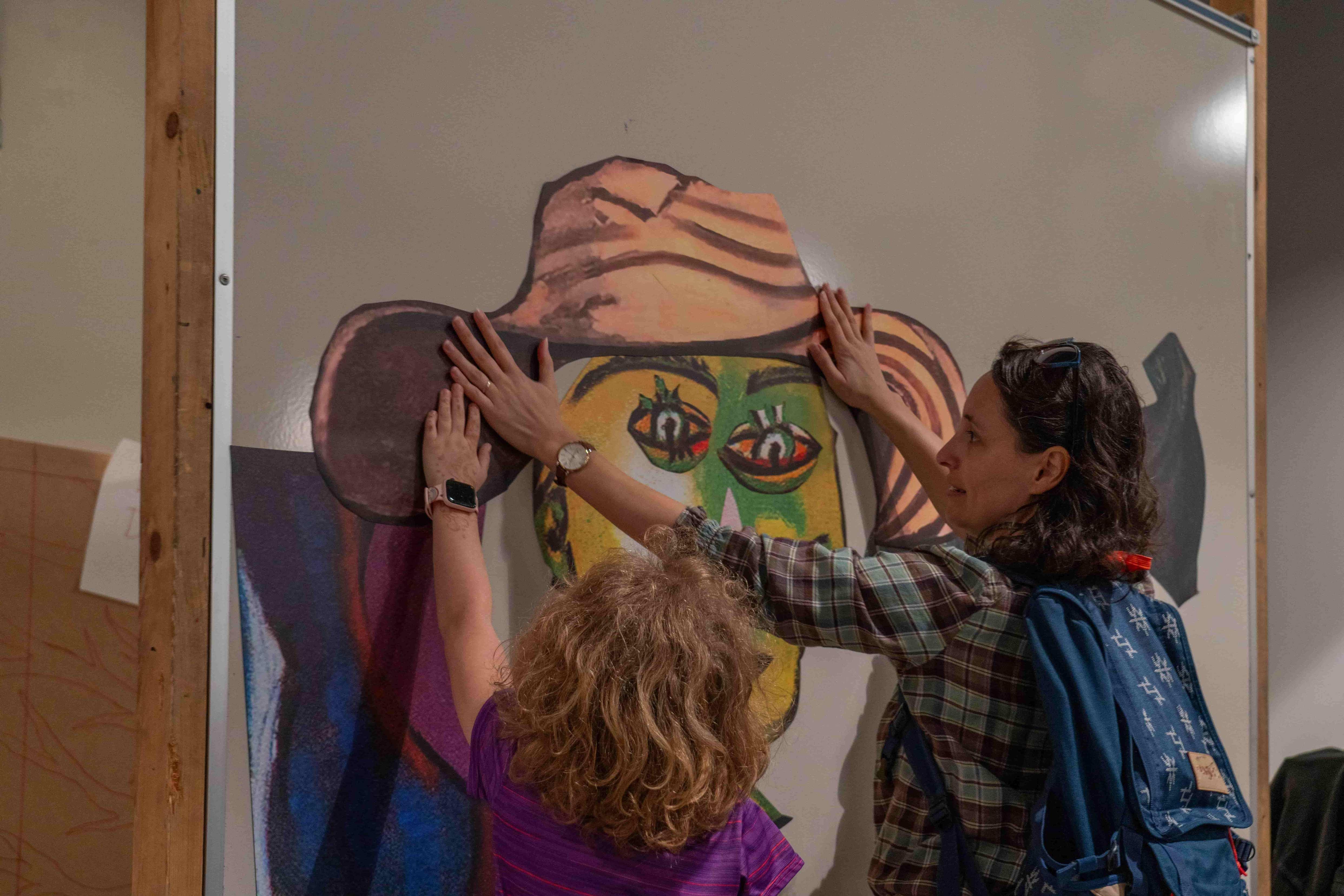 Mother and daughter arranging giant magnets of various Picasso painting body parts to create a new creation.  / 
