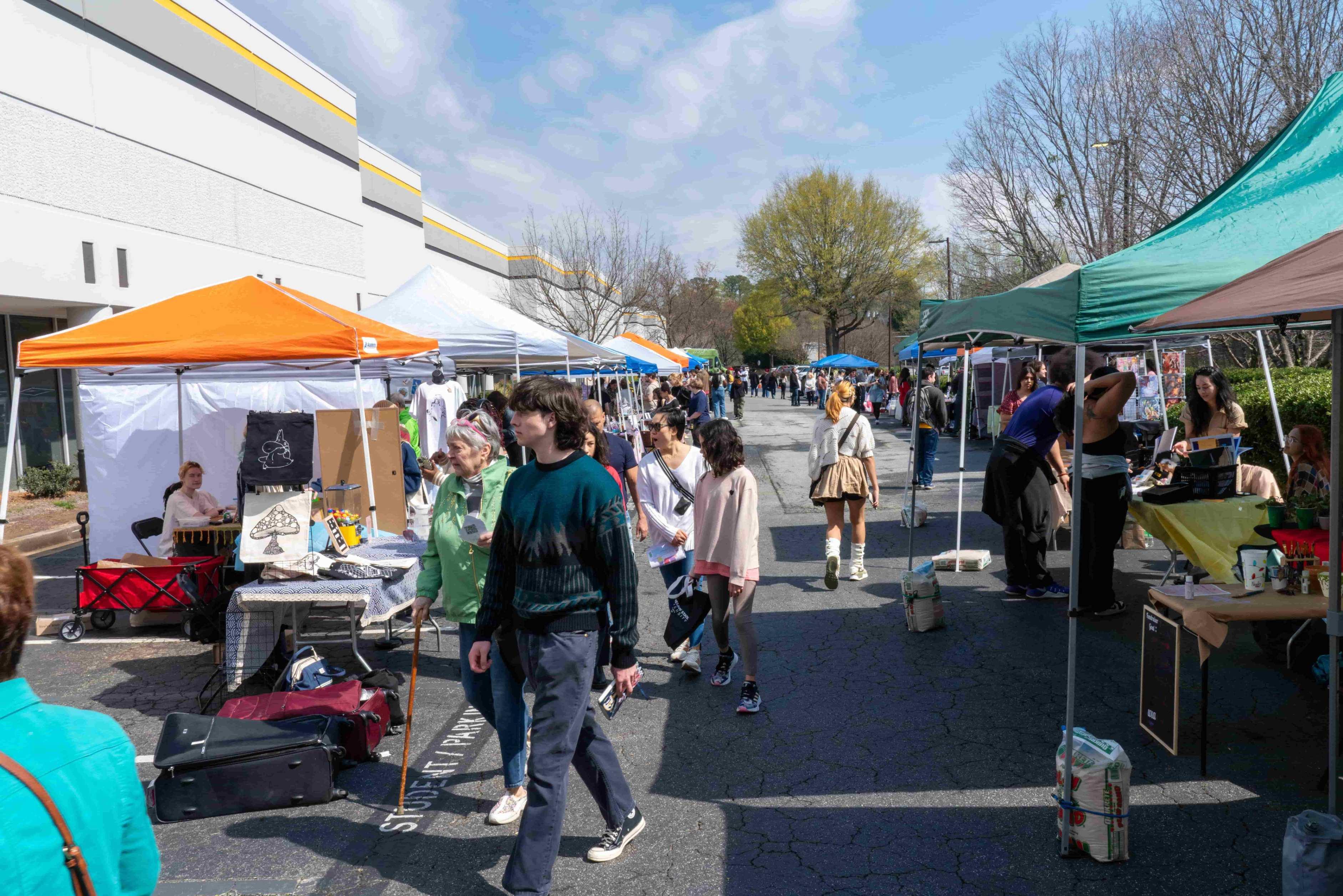 Sunny spring day with student vendor tents in parking lot for the Artist Market. Artist Market is busy with patrons.   / 