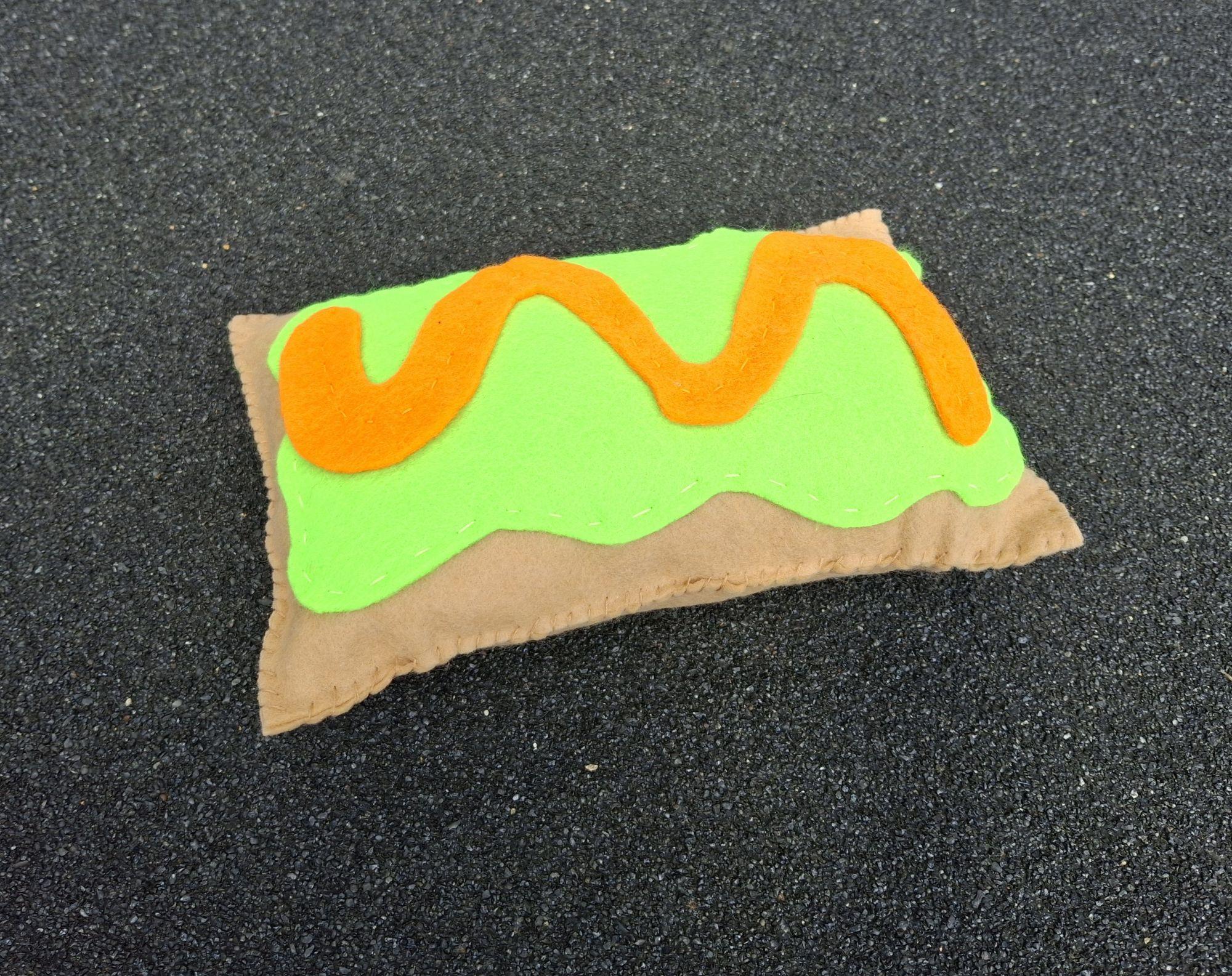 Hand sewn felt pop tart pillow with brown base, green top, and orange wavy line.  / Hand sewn felt pop tart for 7th grade art class.  