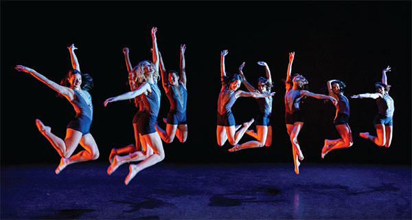 nine dancers jumping in the air on stage
