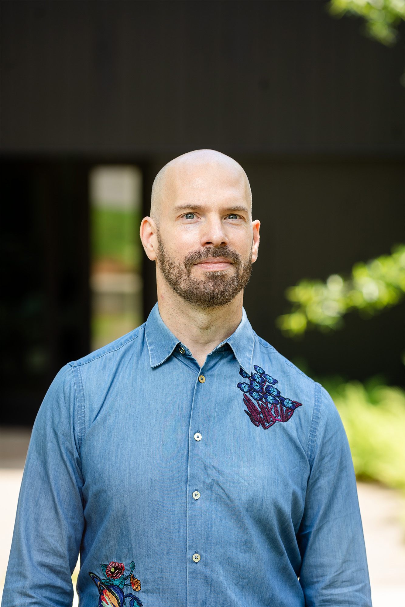 Headshot of a man standing in a walkway outside