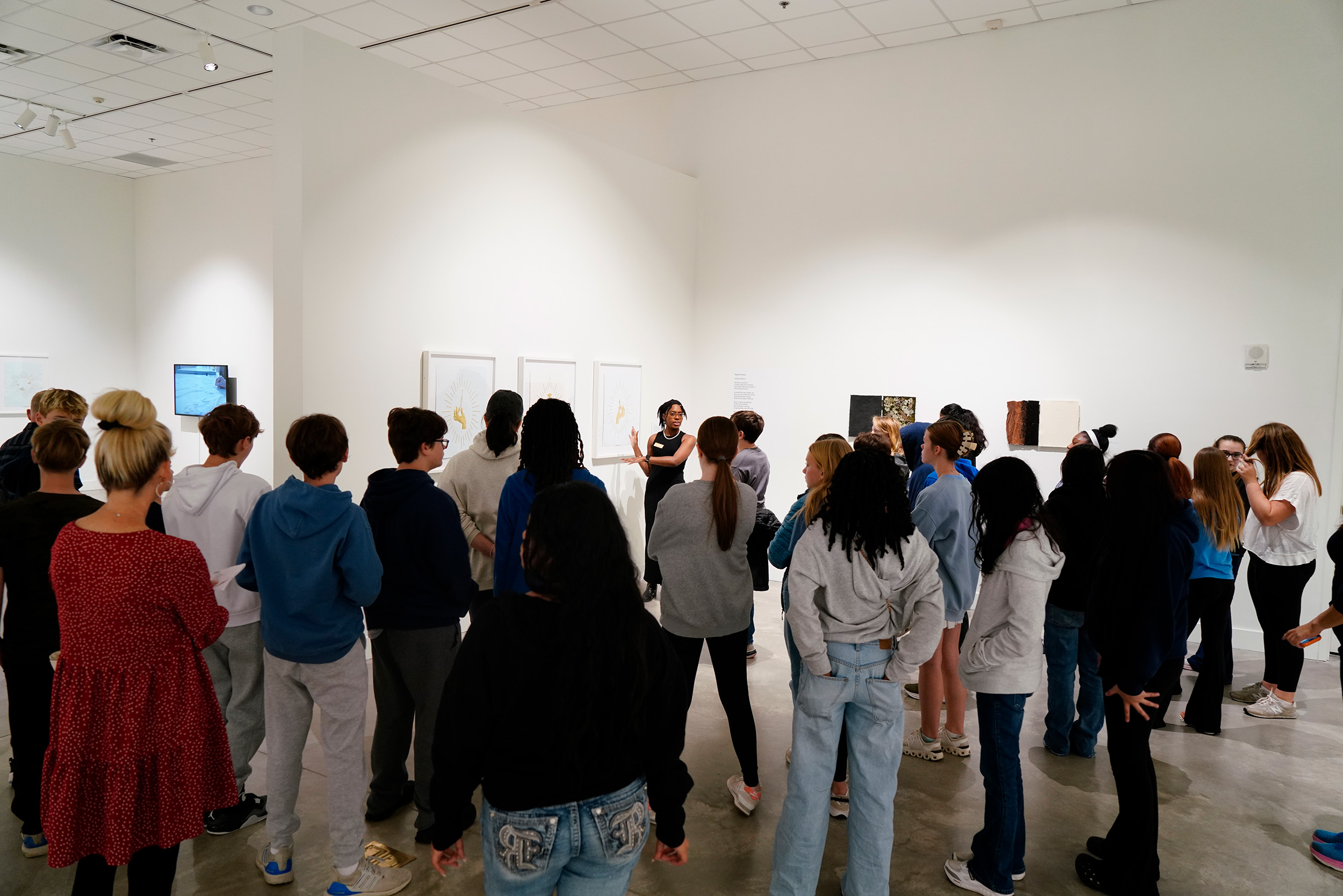 group of children in a gallery while a docent points to artwork and speaks about it