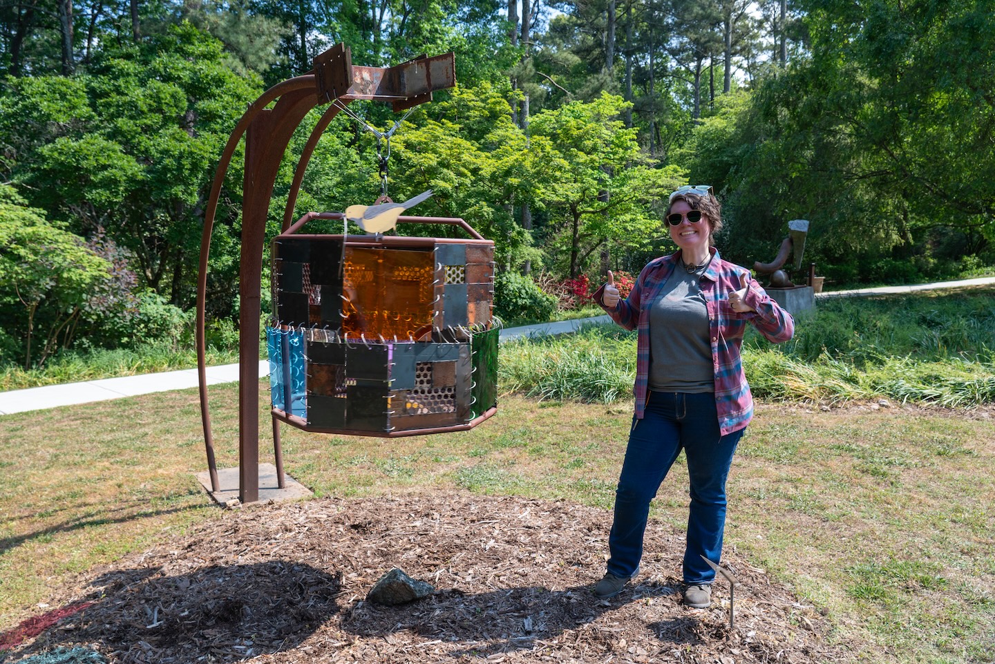 sculpture artists stands beside new installation in a garden