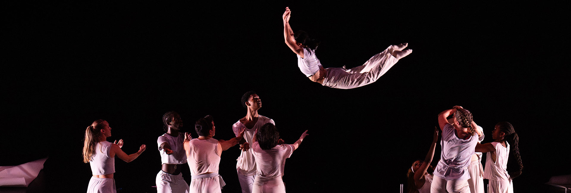 dancers in form on stage catching dancer in air