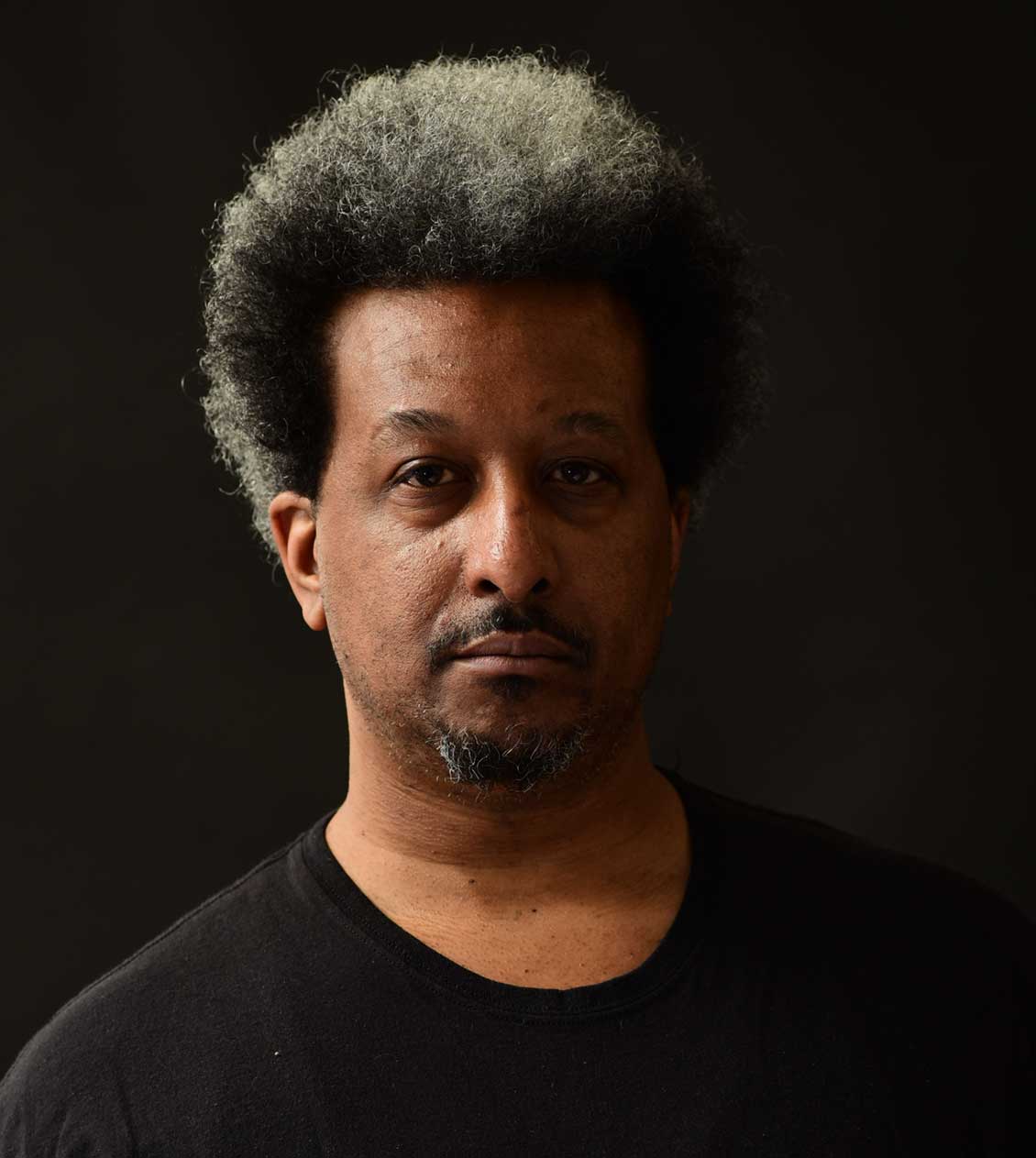 headshot of male african american artist in a black shirt against a black background