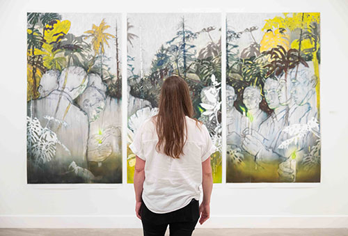 woman standing in front of colorful floral triptych painting