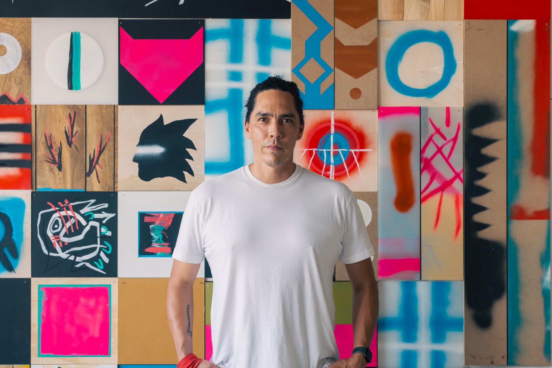 man standing in front of colorful quilt-like paintings