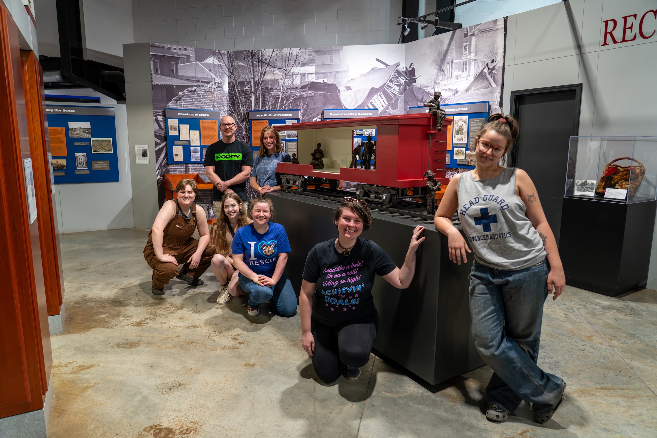 Students gather around a sculpture of a train they completed