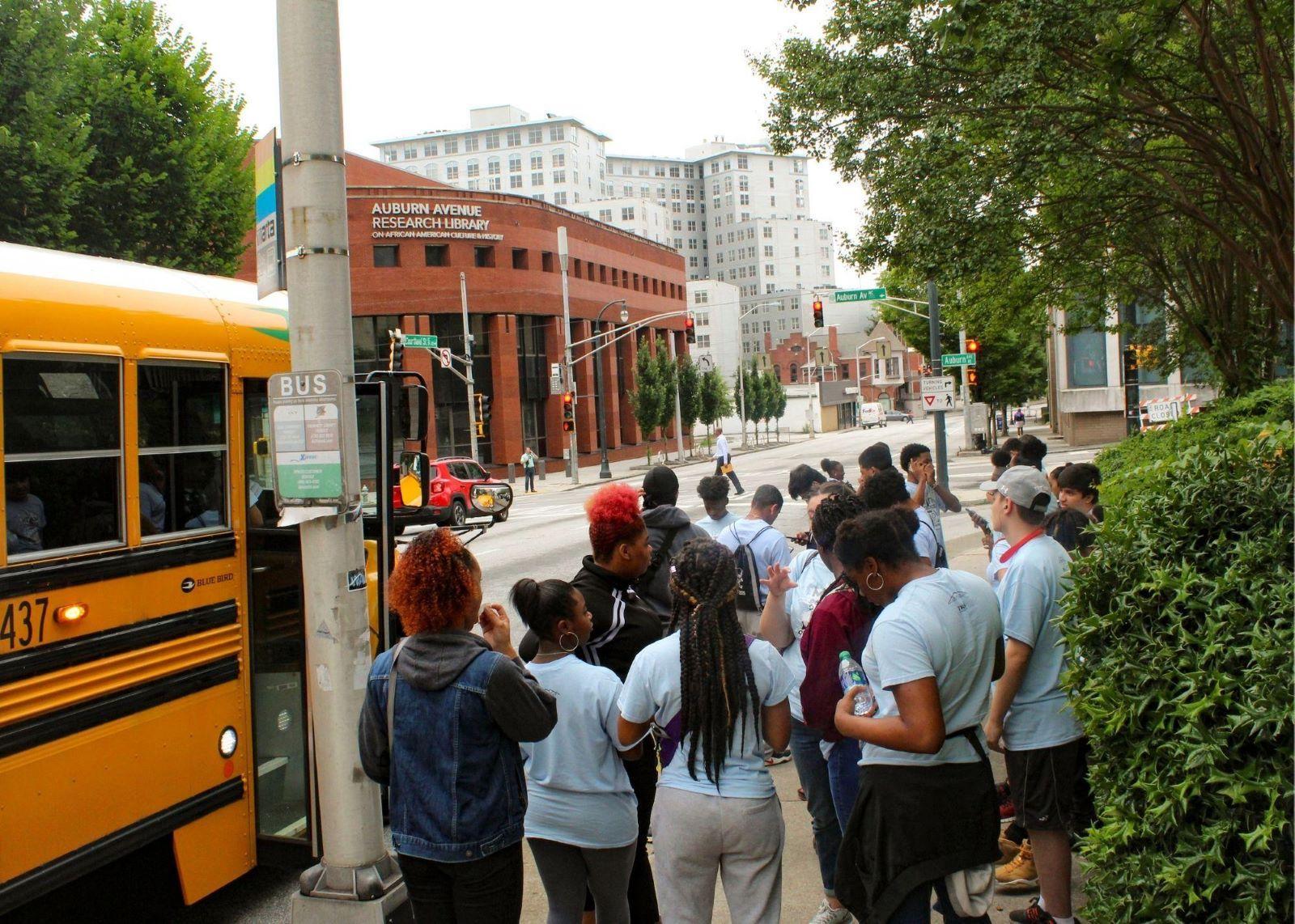 Students standing outside near a school bus.  / KSU TRiO visits Georgia State University, the Civil Rights Museum, and Centennial Park.