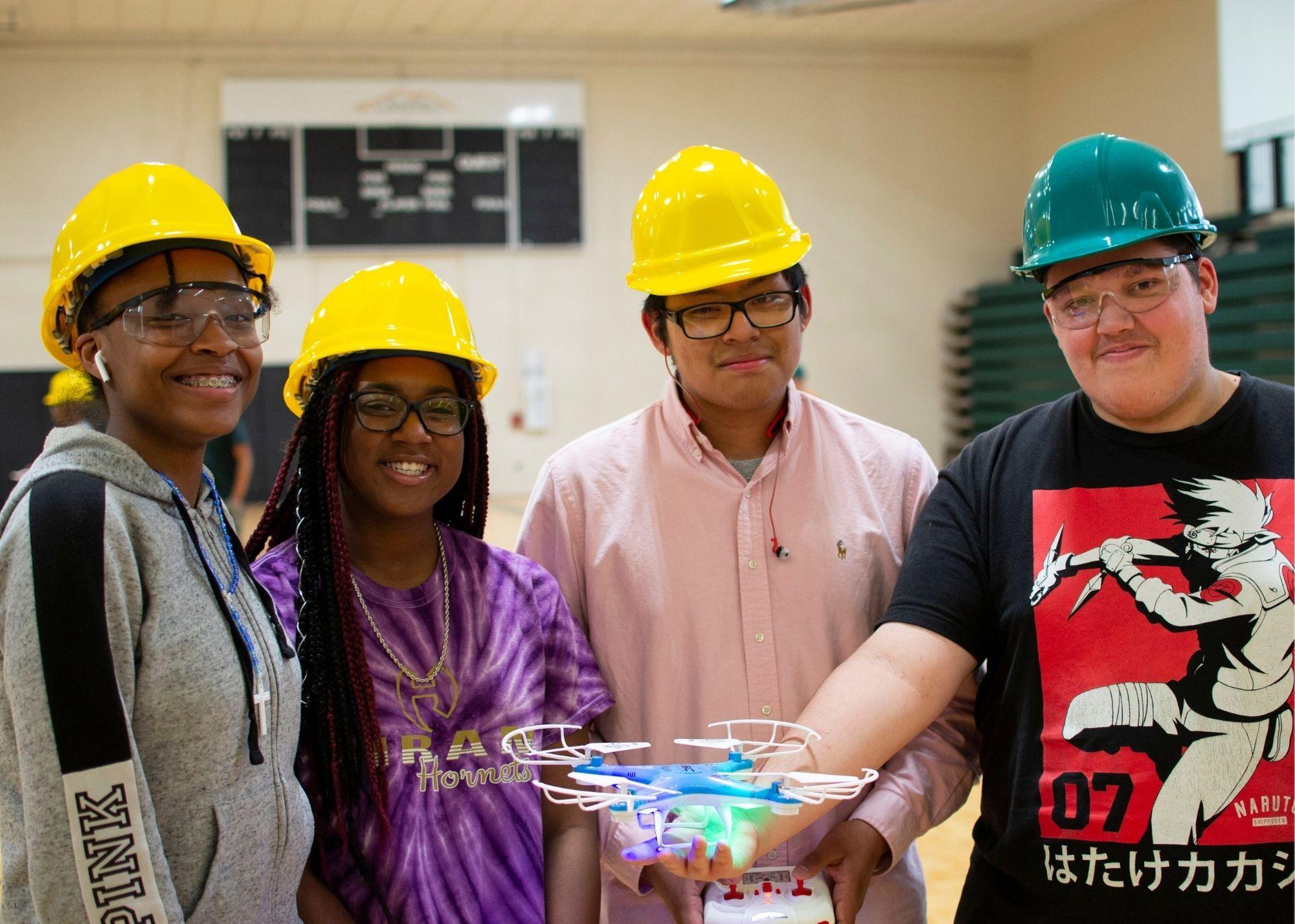 Students wearing hardhats, with one student holding a remote and the other holding a drone  / KSU TRIO's groundbreaking Drone Program introduces students to the basics of drone flying, ethics, and mechanics, and the program gives students the opportunity to test for their FAA Pilot's License 