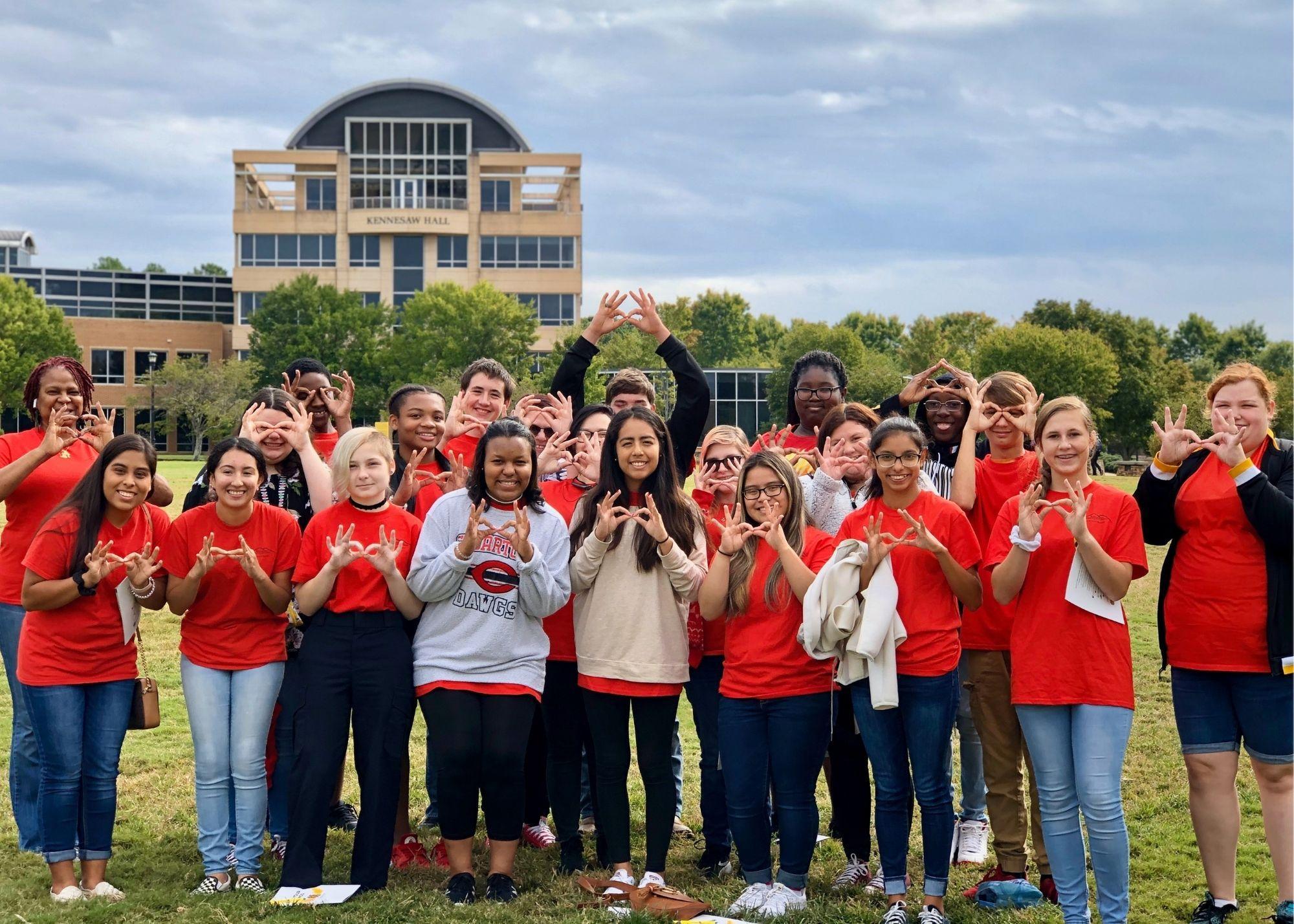 Students in red shirts pose outside in front of the Kennesaw Hall building at KSU  / KSU TRiO Upward Bound at Rockmart and Cedartown High Schools visit Kennesaw State University. 