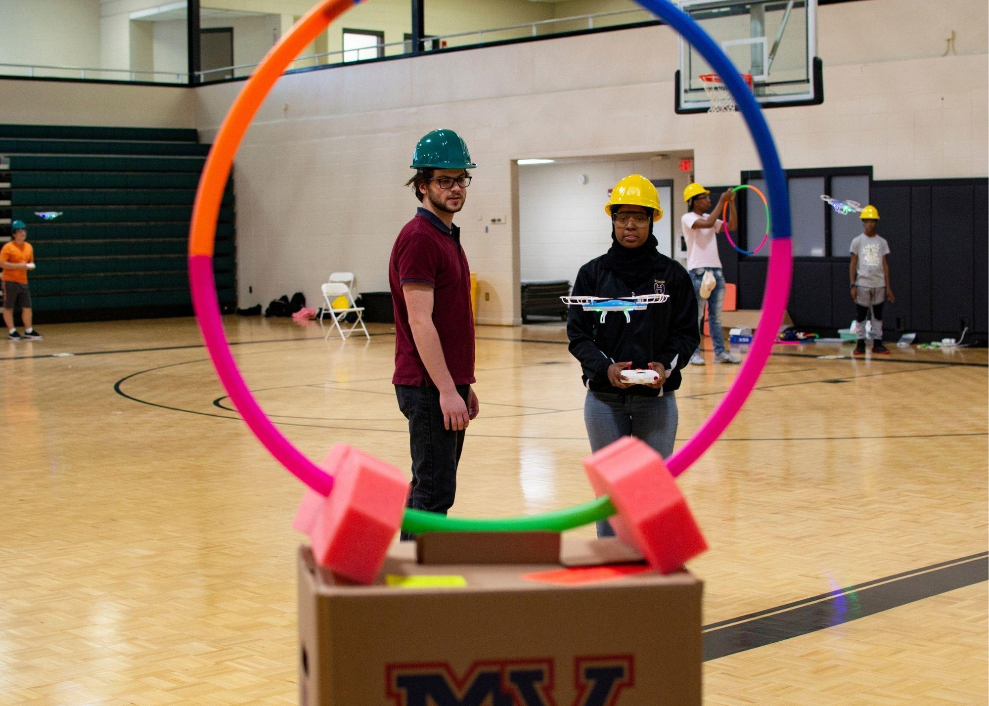 Students in a gym setting wearing hardhats and flying drones  / KSU TRIO's groundbreaking Drone Program introduces students to the basics of drone flying, ethics, and mechanics, and the program gives students the opportunity to test for their FAA Pilot's License 
