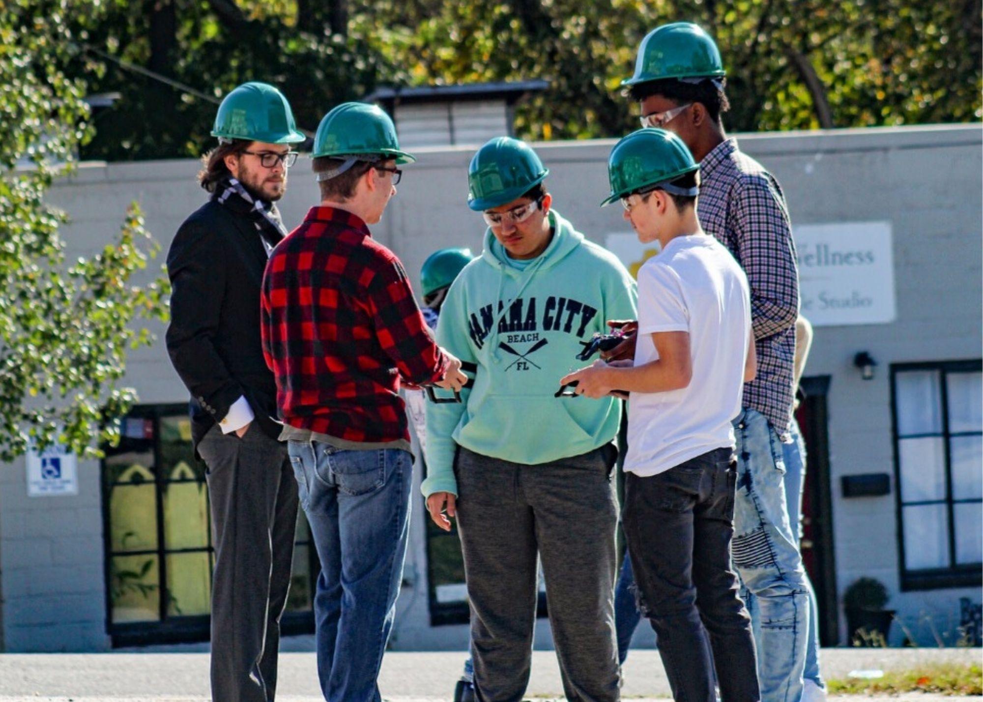 Students and instructor wearing hardhats, learning about the basics of drone flying / KSU TRIO's groundbreaking Drone Program introduces students to the basics of drone flying, ethics, and mechanics, and the program gives students the opportunity to test for their FAA Pilot's License 