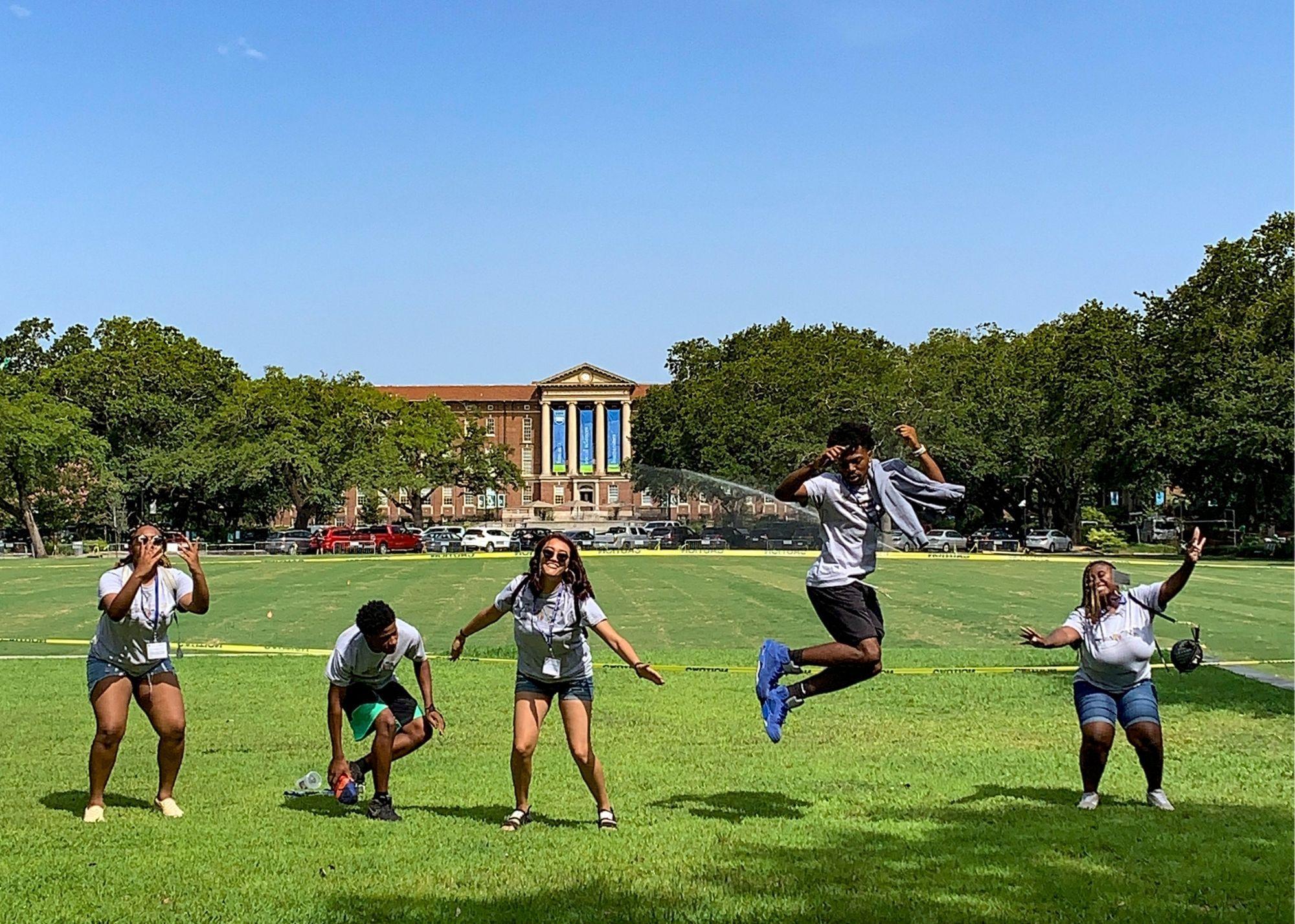 Students on a field smiling and jumping in the air.  / KSU TRIO Students have the opportunity to go on an out of state, educational field trip after full participation in the KSU TRiO Summer Academy. The trip is provided at no cost to students. 