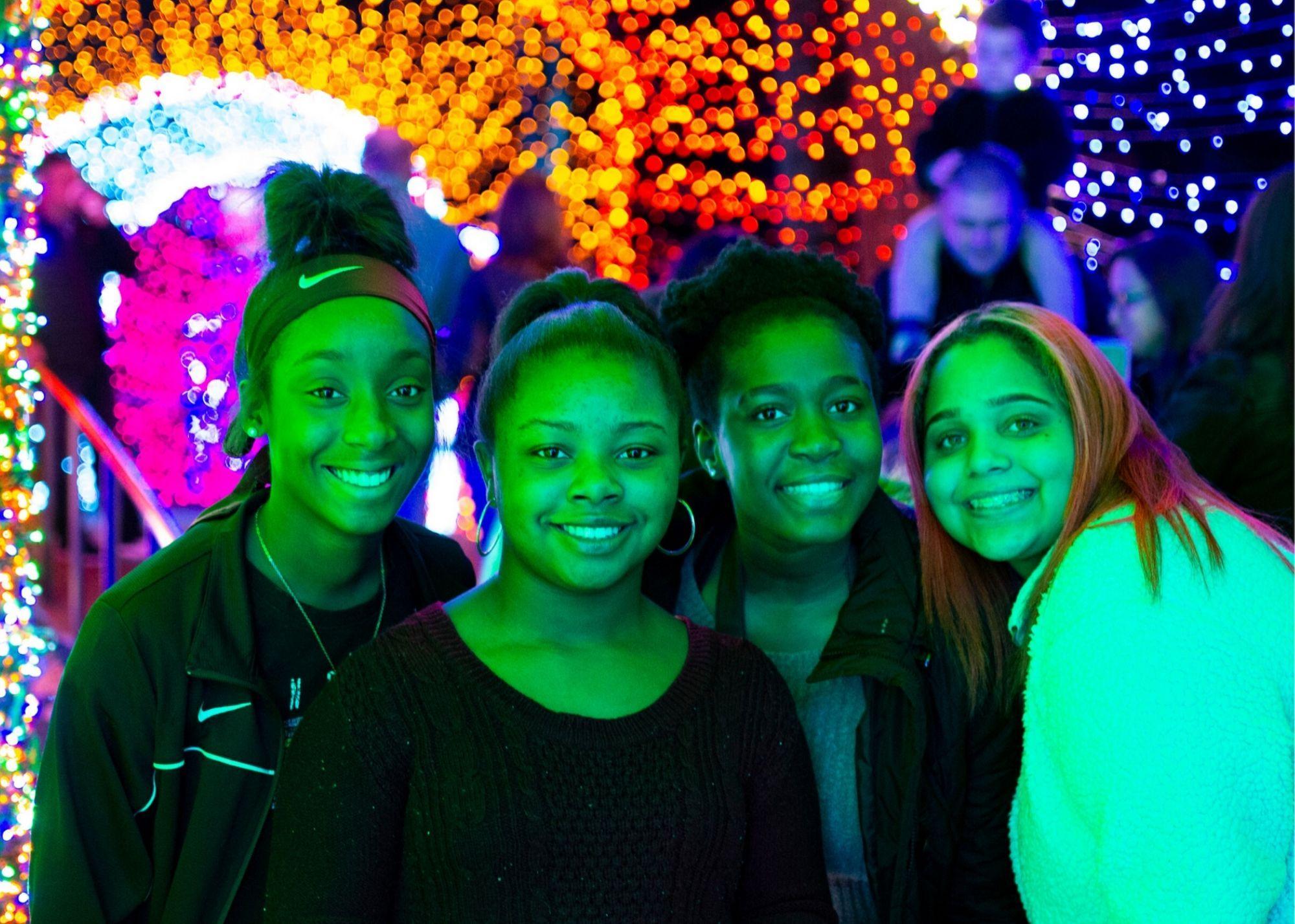 Four students at Atlanta Botanical Gardens with a light display in the background.  / KSU TRIO Students have the opportunity to explore and learn about the science behind the Atlanta Botanical Gardens.