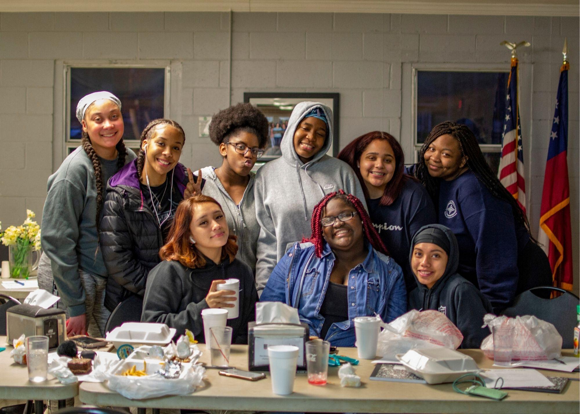 Women smiling in front of a table with food and drinks  / KSU TRiO holds a Women's Empowerment Conference to provide a space space for women to learn and grow. 