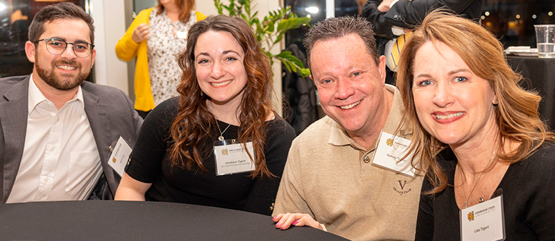 our Bagwell College of Education alumni smiling together at a table, capturing a joyful moment for the camera.