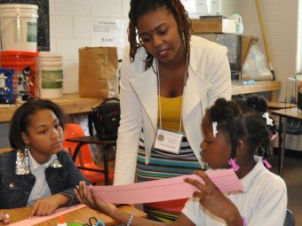 A woman supports two children in their projects, representing the Clarice C. and Leland H. Bagwell College of Education Hall of Fame.