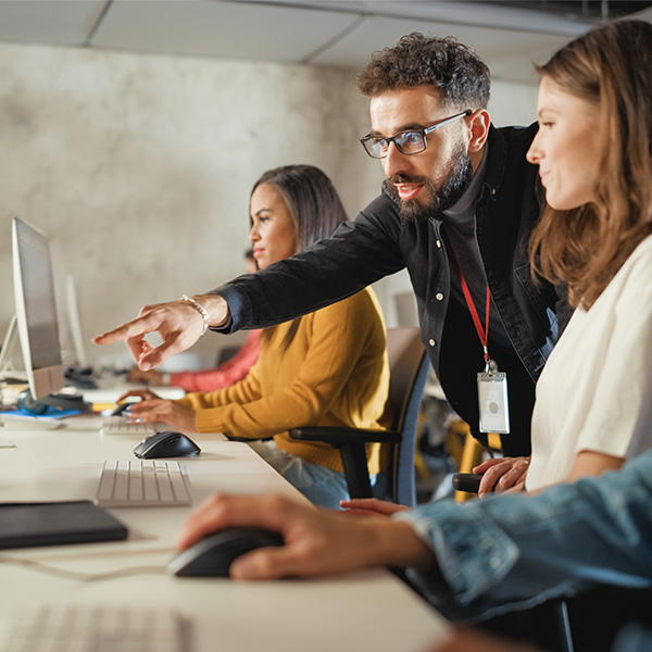Professor working with students in a computer lab setting