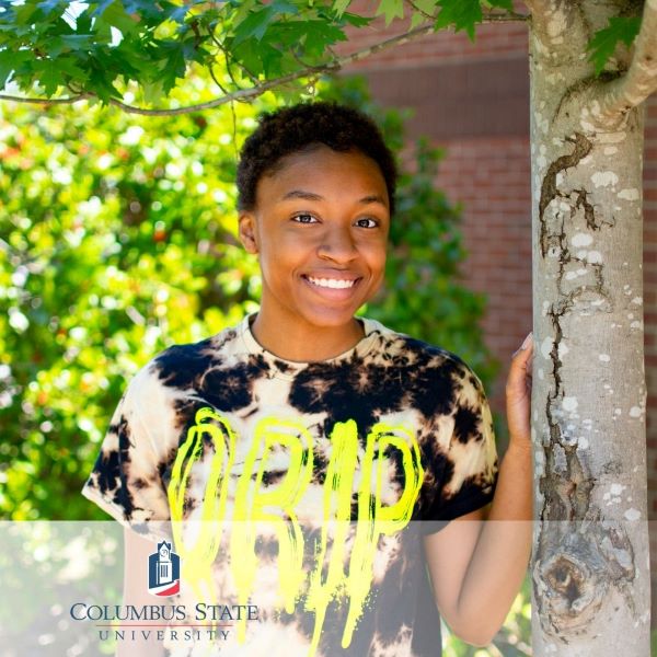 Bre'Yonna Stone, a student standing near a tree with the Columbus State University logo in the bottom left corner.