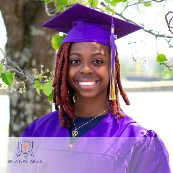 Destiny Hanna, a smiling graduate in a purple cap and gown, with the Brewton Parker College logo in the bottom left corner. 