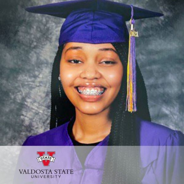 Danamei Wright, a graduate in a purple cap and gown, with the Valdosta State University logo in the bottom left corner.