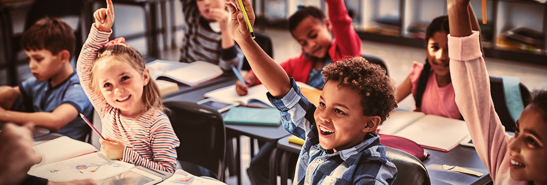 elementary children raising hand in class