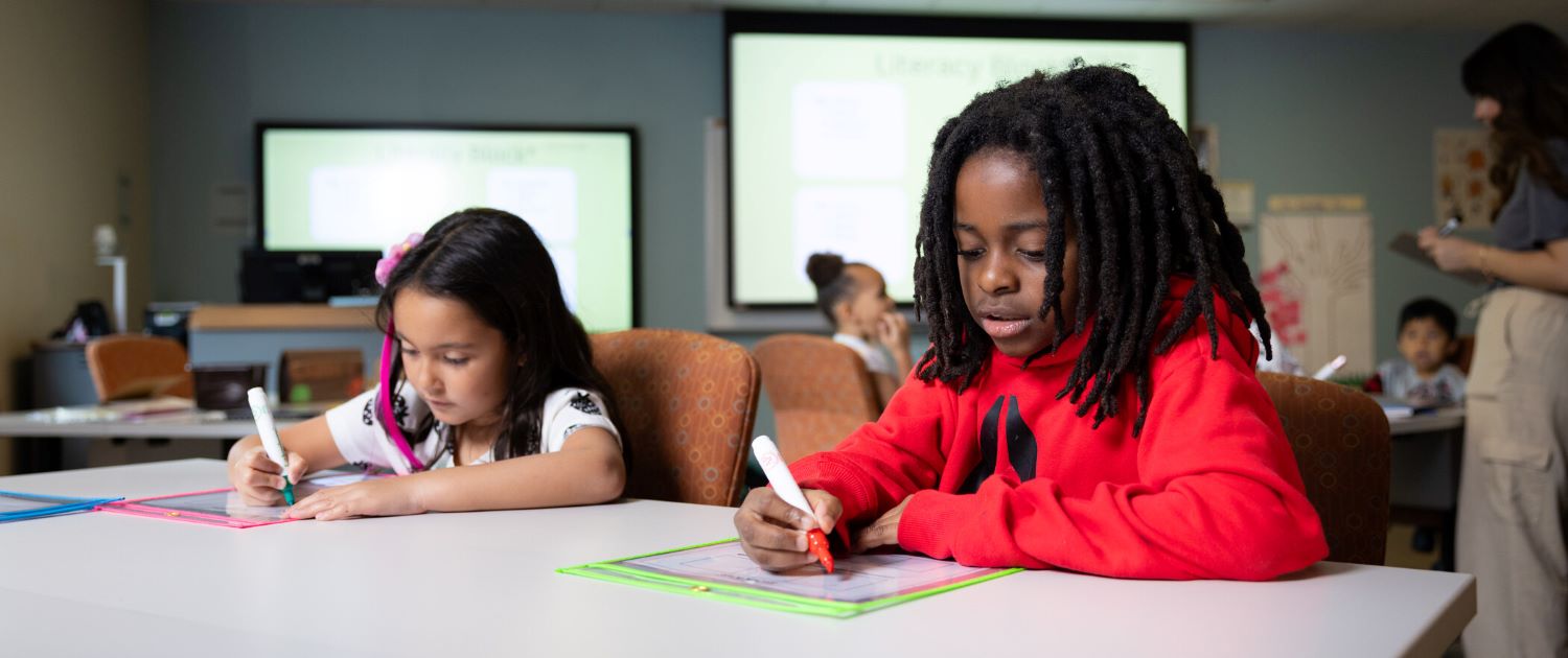Two young students doing a writing activity in a classroom.