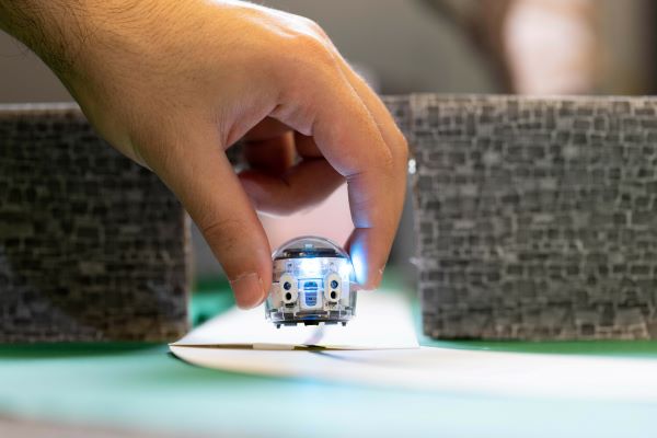 A hand grips a small robot toy