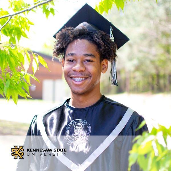 Jonathan Fleurimont, a graduate wearing a cap and gown with the Kennesaw State University logo in the bottom left corner.
