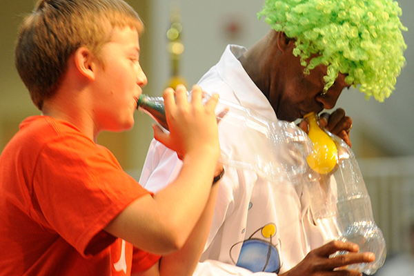 master secondary science man in green wig showing kids science project