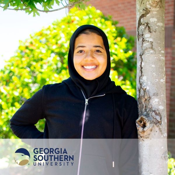 Saalihah Abdus-Shaheed, a student standing near a tree with the Georgia Southern University logo in the bottom left corner.
