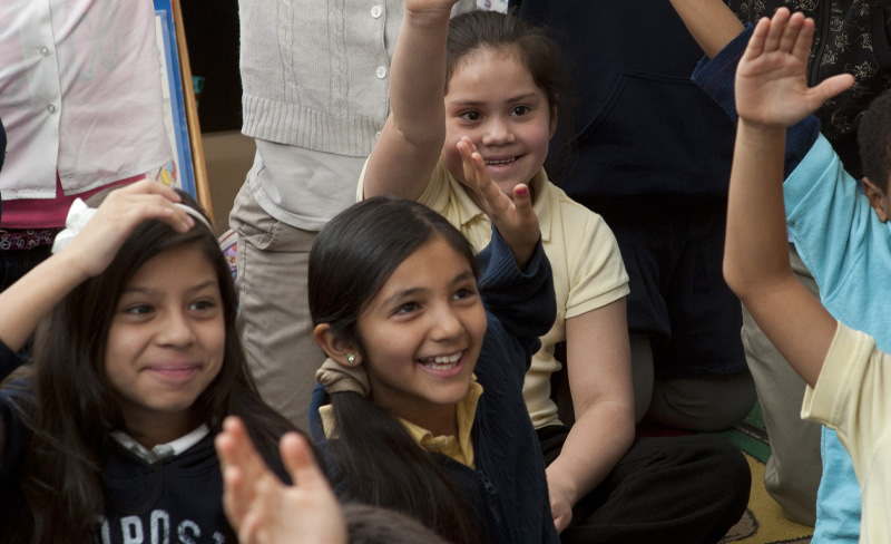 small students raising hands