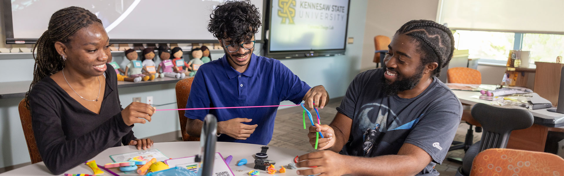 ksu students sitting at a table at the ud lab working on a project.