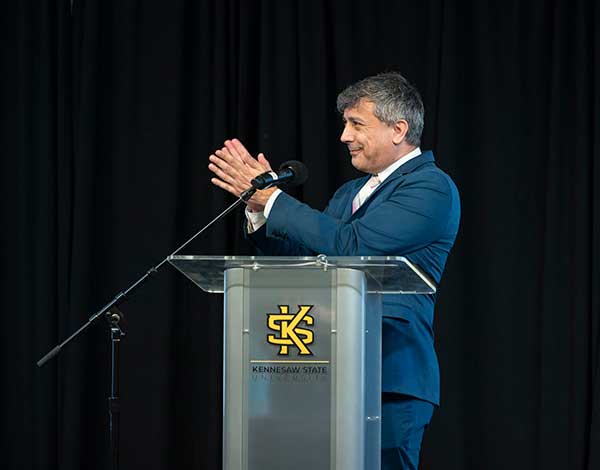 professor clapping at podium during ksu event