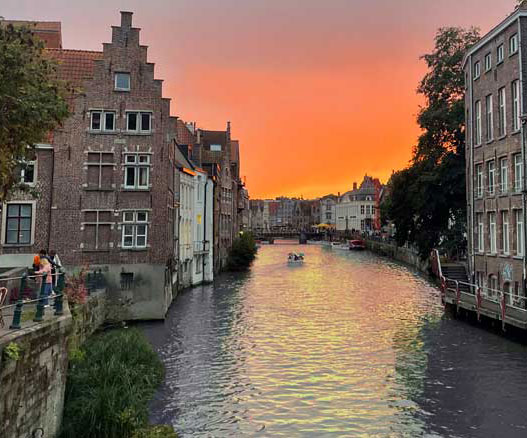 A serene canal in Bruges, Belgium, illuminated by the warm hues of sunset, reflecting the beauty of study abroad experiences.