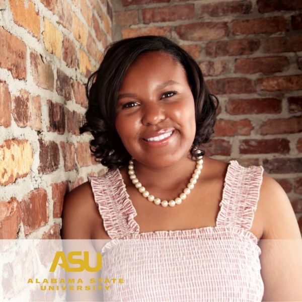 Asia Turner, smiling and leaning against a brick wall, with the Alabama State University logo in the bottom left corner. 