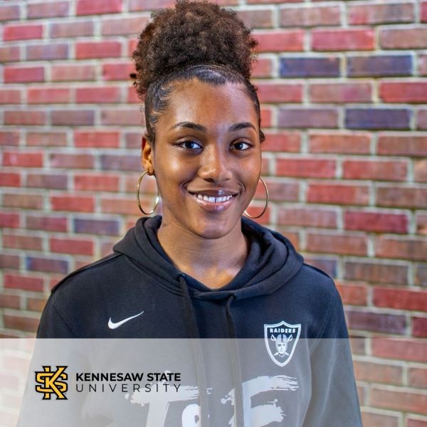 Amaia Ward, smiling in a headshot with a brick wall background, and the Kennesaw State University logo in the bottom left corner.