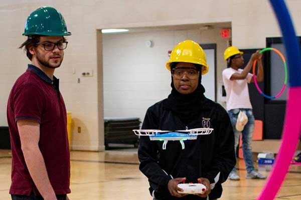 students flying drone through hoop