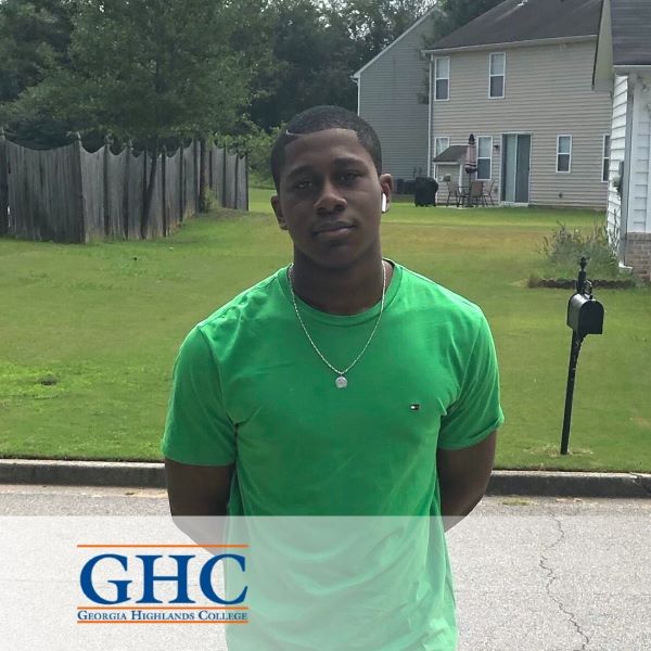 David Gyebi, wearing a green shirt in an outdoor setting with the Georgia Highlands College logo in the bottom left corner.