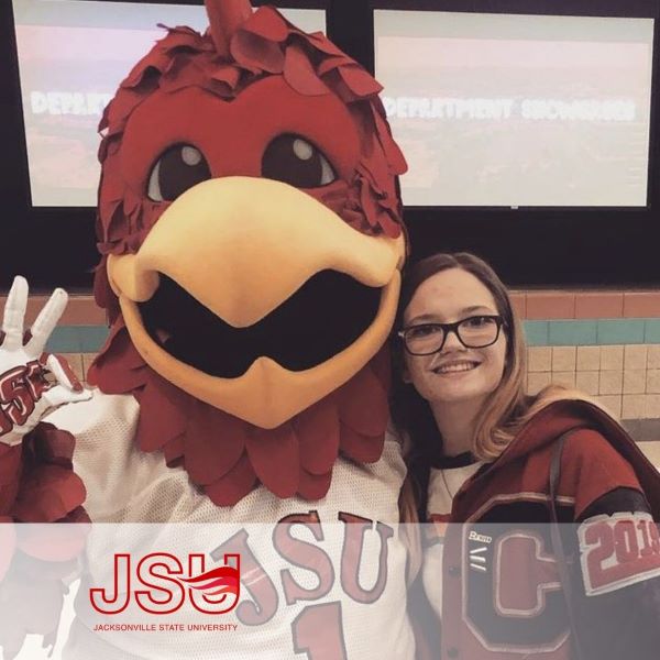 Emily Bentley, smiling and standing with JSU's rooster mascot, with the Jacksonville State University logo in the bottom left corner. 
