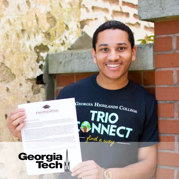 Edward Denzell Dascanio, smiling and leaning against a brick wall with the Georgia Tech logo in the bottom left corner.