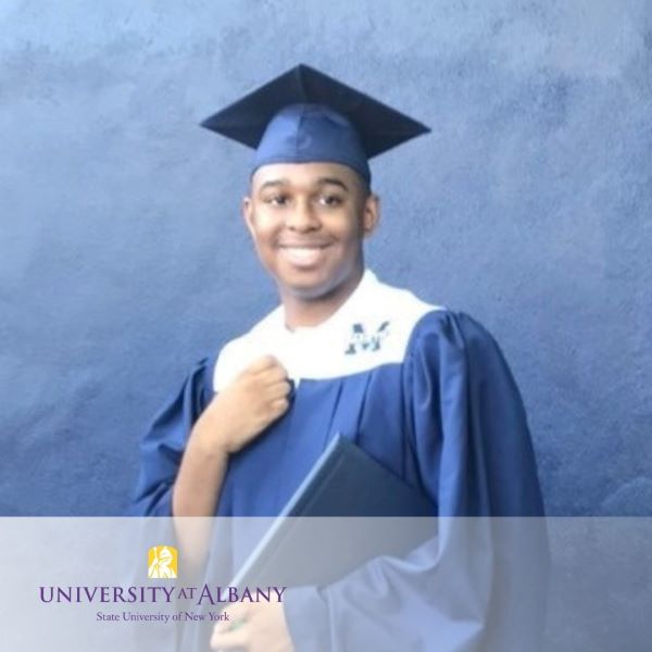 Kaylon Cotton, smiling and wearing a blue cap and gown with the University at Albany logo in the bottom left corner.