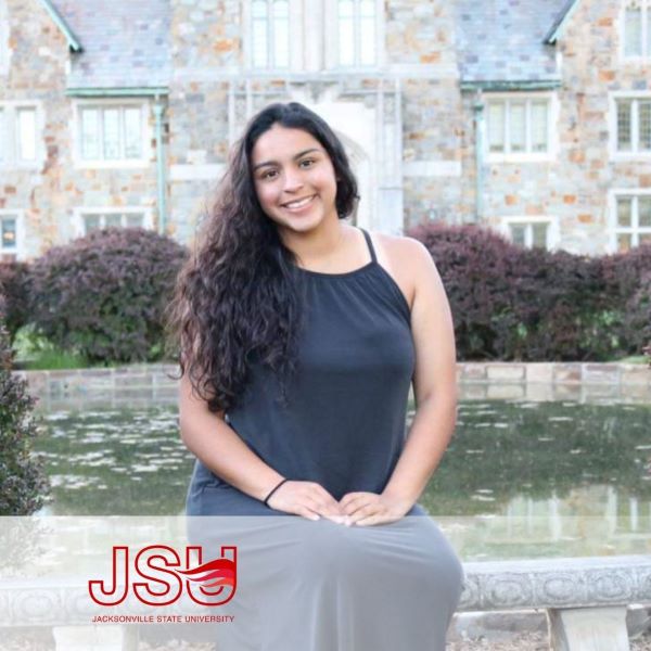 Maria Escutia a student smiling and sitting on a bench near water.