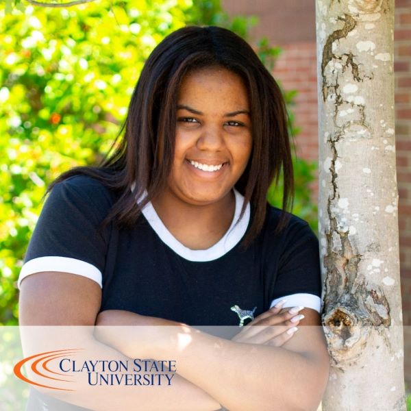 Miracle Weeks, smiling and standing near a tree in an outdoor setting.