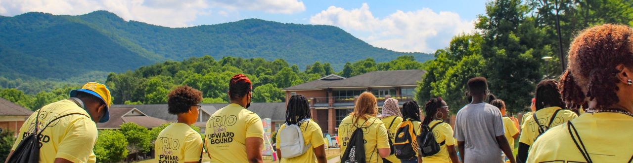 A group of students wearing yellow shirts standing in front of a mountain backdrop.