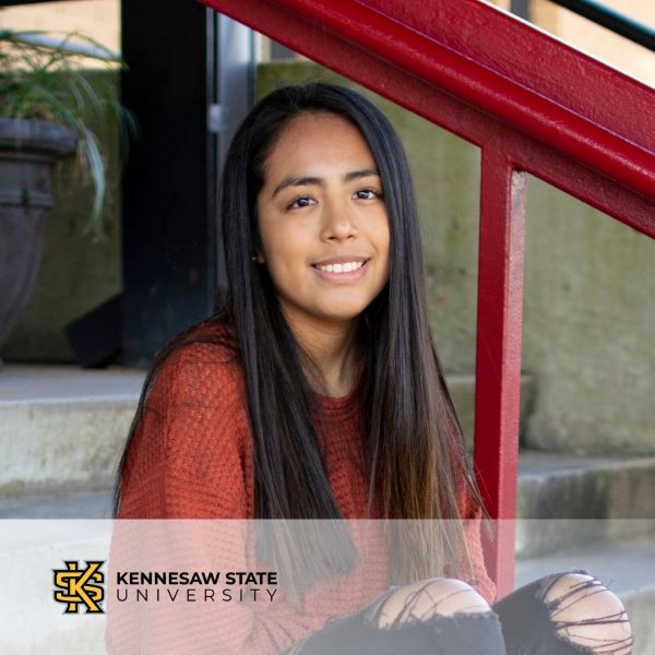 Vanessa Rodriguez, smiling and sitting on steps, with the Kennesaw State University logo in the bottom left corner.