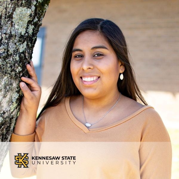 Yesenia Ortiz, smiling in a headshot leaning against a tree, with the Kennesaw State University logo in the bottom left corner.