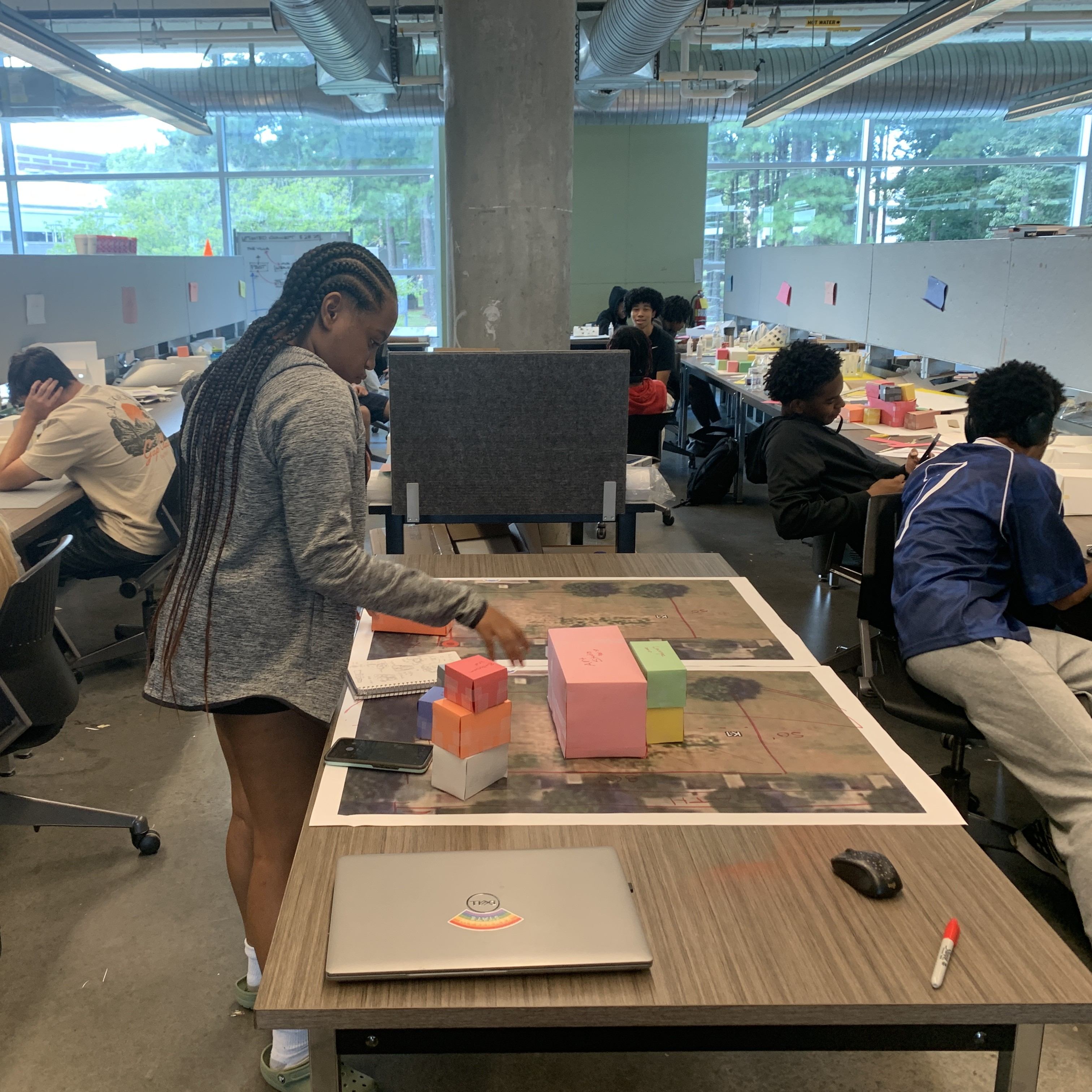 Students work on various architectural models at their studio stations. 